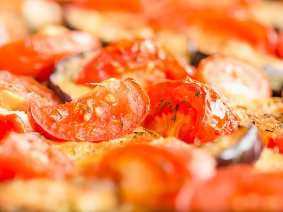 Vibrant close-up of roasted tomatoes and vegetables with fresh herbs.