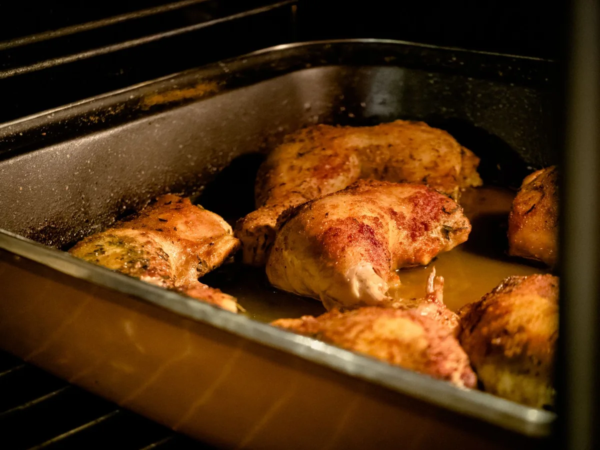 Seasoned chicken legs roasting in a tray inside an oven