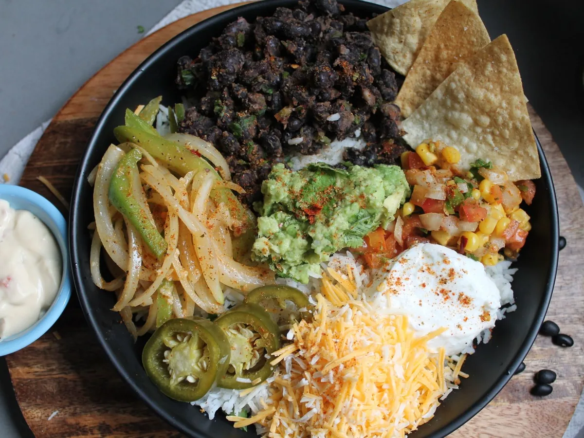 Colorful Mexican-style bowl with black beans, guacamole and cheese