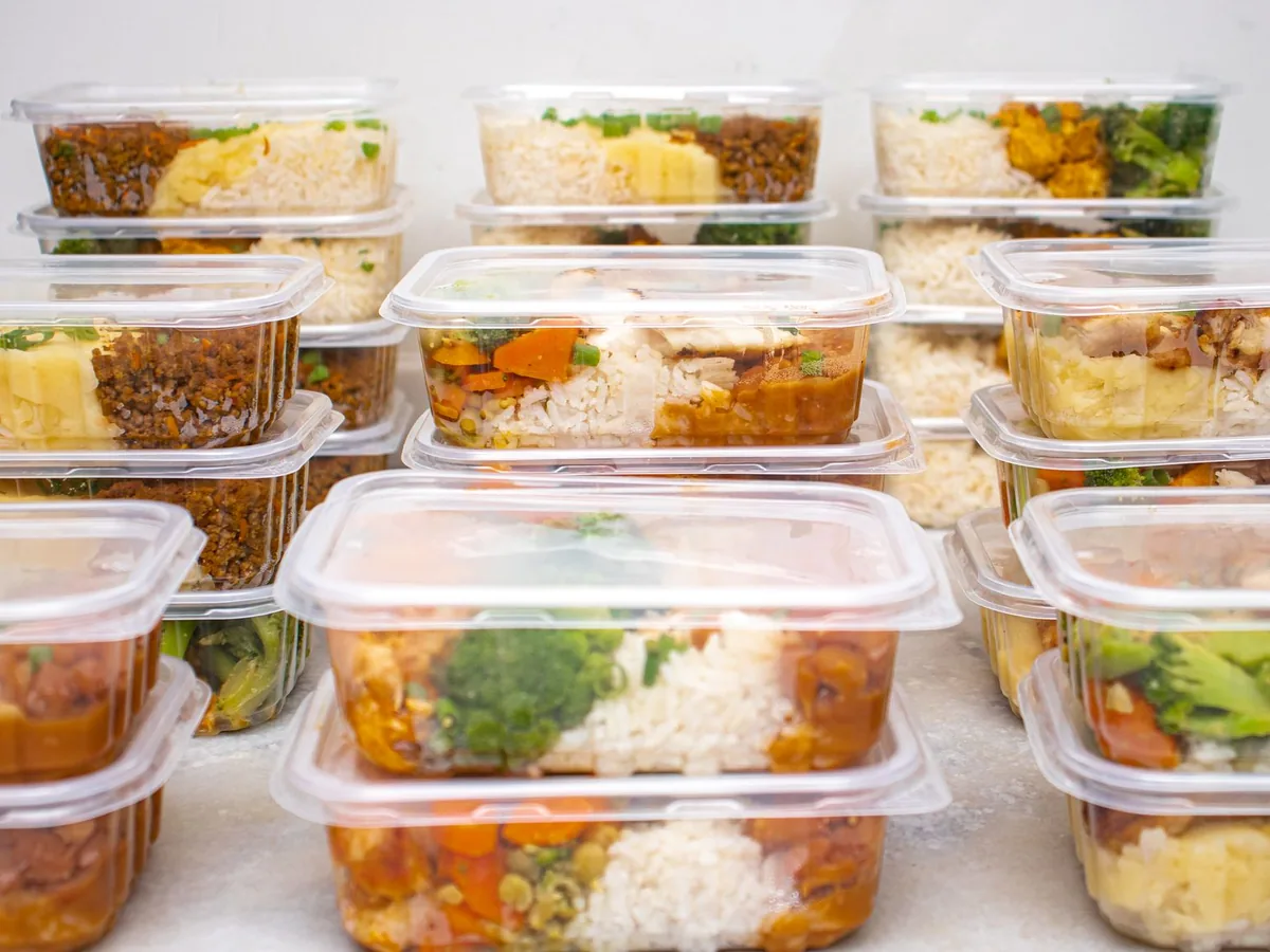 A stack of meal prep containers filled with rice and vegetables.