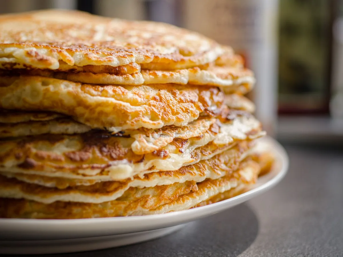 A tall stack of homemade pancakes on a white plate