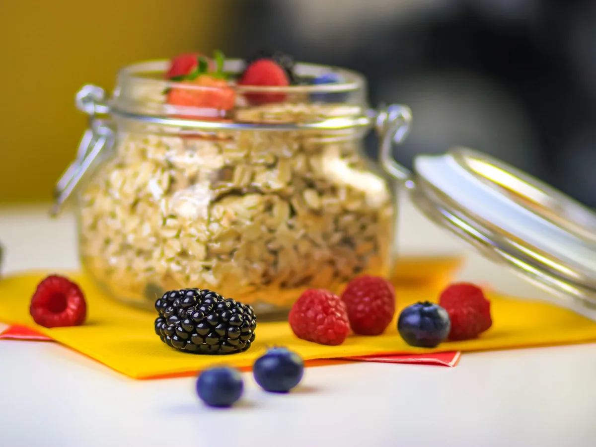 A glass breakfast jar layered with oats and fresh berries.