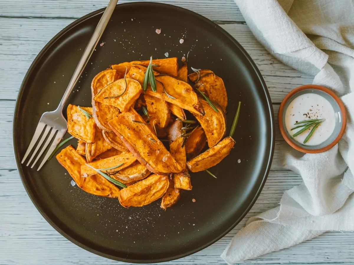 Crispy sweet potato fries with rosemary on a black ceramic plate