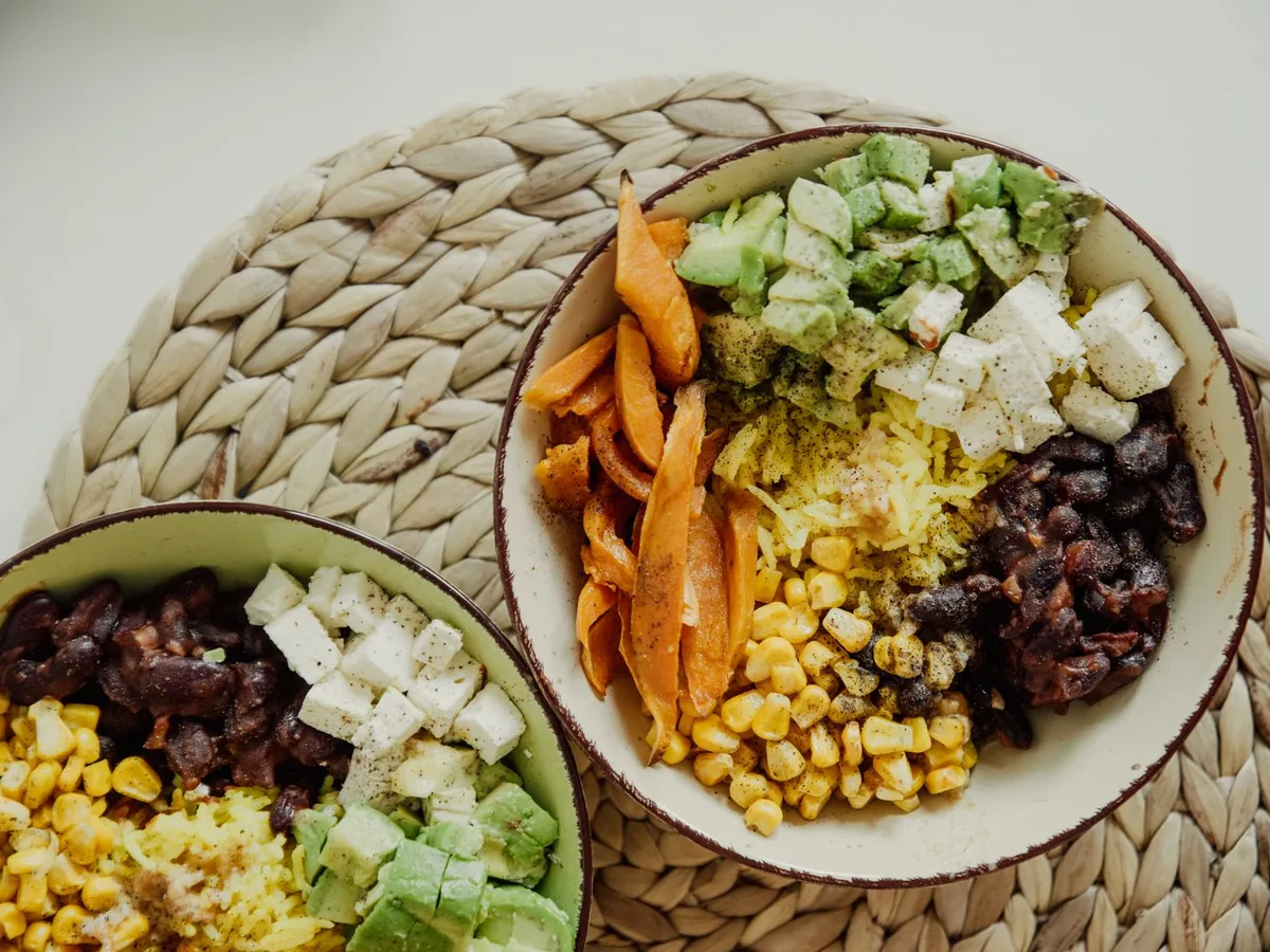 Overhead view of vegetarian bowls with avocado, corn, beans, and cheese